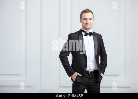 Attraktiven jungen Mann im Smoking und lächelnd in die Kamera zuhause suchen Stockfoto