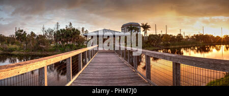 Sonnenuntergang über Pavillon auf einer hölzernen abgeschiedenen, ruhigen Promenade Stockfoto