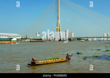 Lokales Boot mit einer Person Rudern in einem Boot in der Nähe der grossen Brücke Span auf dem Chao Praya Fluss in Bangkok. Stockfoto