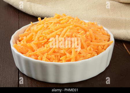 Eine Schüssel mit geriebenem sharp Cheddar Käse auf einem rustikalen Holzmöbeln Zähler Stockfoto