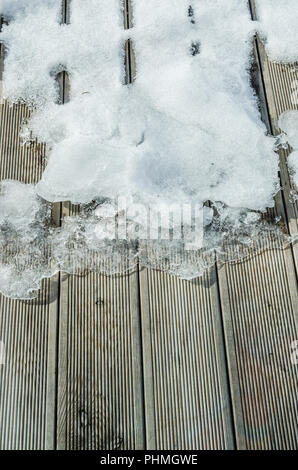 Schmelzender Schnee auf einer hölzernen Terrasse, close-up Stockfoto