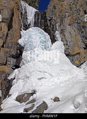 Bizarre Eis bildet sich auf dem Hintergrund der Felsen mit Spritzern von Wasser im Winter in den Bergen. Stockfoto