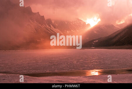 Größe der Natur Konzept: Sonnenuntergang auf einem zugefrorenen See in den Bergen. Stockfoto