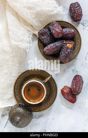 Getrocknete Datteln auf einer Bronzetafel und schwarzen Kaffee. Stockfoto