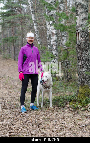 Sportliche Frau mit einem Hund im Park Stockfoto