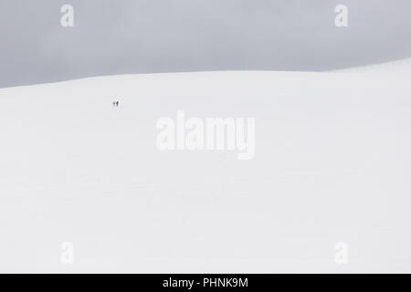 Ein sehr minimalistisches Blick auf zwei weit entfernte Menschen über einen Berg von Schnee bedeckt Stockfoto