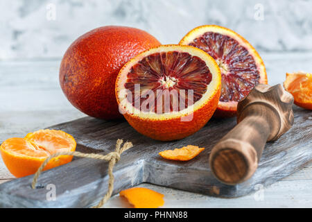 Ganze oder halbe Blutorange und Zitruspresse. Stockfoto