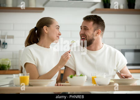 Liebevolle junge Frau Fütterung bärtigen Mann beim Frühstück in der Ho Stockfoto