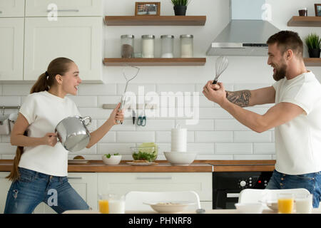 Verspielte junge Paar spielen mit Geschirr in der Küche Stockfoto