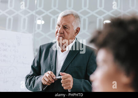 Senior Manager im Sitzungssaal während der Präsentation und Diskussion von Kollegen. Reifen Geschäftsmann in Konferenzraum während eines Stockfoto