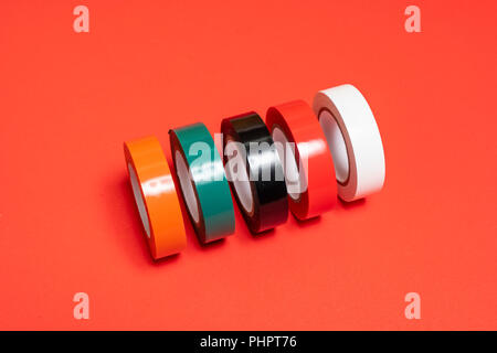 Einige Rollen von farbigen Isolierband auf eine rote Fläche Stockfoto