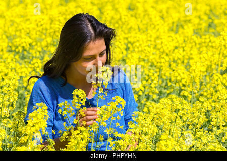 Frau riecht Blume in gelber Raps Feld Stockfoto