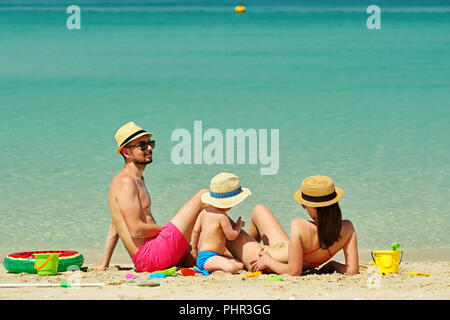 Familie am Strand. Kleinkind spielen mit Mutter und Vater. Stockfoto