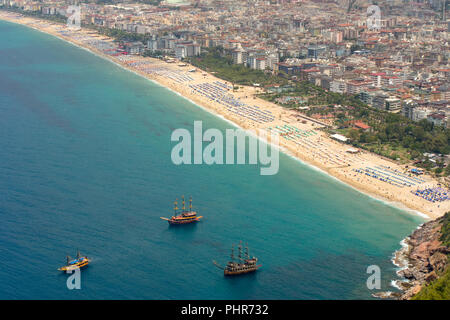 Ein Blick von Oben auf ein beliebtes Hotel gesäumten Strand von Alanya, Türkei mit 3 touristische Sehenswürdigkeiten Schiffe vor der Küste nur verankert. Stockfoto