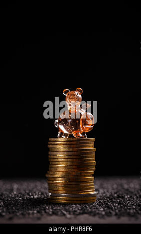 Golden bitcoins liegen in einem Haufen mit kleine Schweinchen auf dunklem Hintergrund Stockfoto