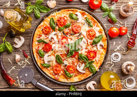 Flach mit italienischen Pizza auf Holzbrett und verschiedene Zutaten Stockfoto