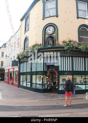 Eine Dame wartet bereit, mechanische Uhr auf Rivoli Juweliere St. Helier, die auf die Stunde dreht sich animierte Szenen von Jersey Leben Anzeige zu sehen Stockfoto