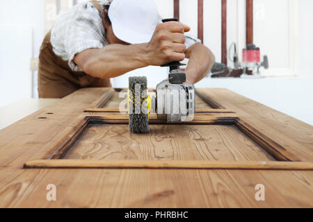 Carpenter das Holz mit dem Schleifer schleifen Elektrowerkzeuge für rustikale Holz- Effekte arbeiten Stockfoto