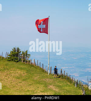 Mt. Rigi, Schweiz - 19. Juli 2018: einer Person, die bei einer Flagge der Schweiz auf dem Mt. Rigi. Die Rigi ist ein beliebtes Ziel für Touristen zugänglich b Stockfoto