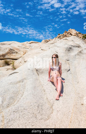 Sommer lifestyle Portrait von hübsche junge Frau. Das Leben genießen und sich auf den Felsen der tropischen Insel. Stockfoto