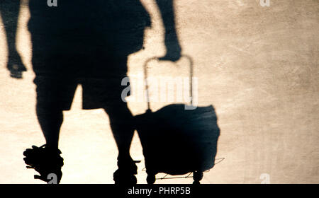 Schatten Silhouette der ältere Mann ziehen einen Einkaufswagen grocery Bag, von der Taille abwärts in sepia schwarz und weiß Stockfoto