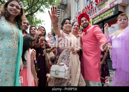 Die Familie & Freunde von einem Sikh Bräutigam feiern Sie mit Gesang und Tanz vor ihm Begleitung Tempel für seine Hochzeit. In Queens, New York City. Stockfoto