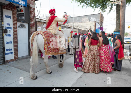 Gemäß der Tradition, ein Sikh Bräutigam auf einem weißen Pferd zu seiner Hochzeit folgt eine Prozession von seiner Familie und seinen Freunden. In Richmond Hill, Queens, NY Stockfoto