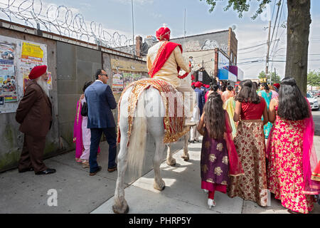 Gemäß der Tradition, ein Sikh Bräutigam auf einem weißen Pferd zu seiner Hochzeit folgt eine Prozession von seiner Familie und seinen Freunden. In Richmond Hill, Queens, NY Stockfoto