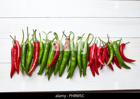 Chili peppers in einer Reihe auf einem weißen Holz- Hintergrund Stockfoto