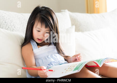 Glücklich süsse kleine Mädchen lächelnd und mit roten Bleistift und Zeichnen, Schreiben auf ein Buch, um Hausaufgaben zu machen. kid Bildung Konzept. Stockfoto