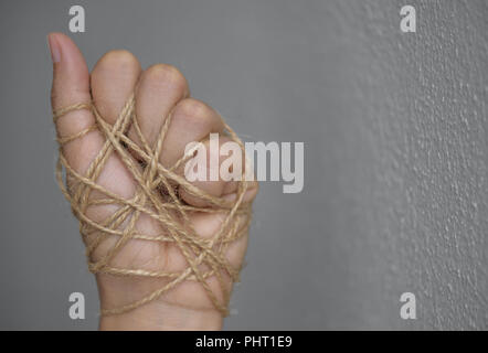 Frau Hand gebunden mit Draht auf dunklem Hintergrund in Low Key. Internationaler Tag der Menschenrechte Konzept. Stockfoto