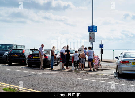 Die Leute Schlange stehen an einem pay Station an einem sonnigen Tag am Meer. Stockfoto
