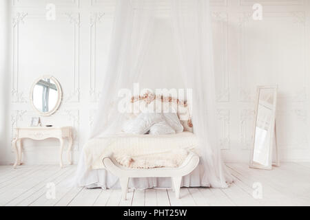 Schlafzimmer in warmen hellen Farben. großes bequemes Doppelbett im eleganten klassischen Schlafzimmer Stockfoto