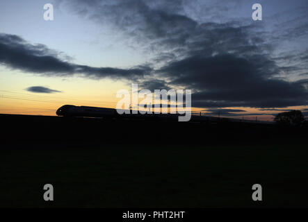 Ein Virgin Trains Pendolino train auf der West Coast Main Line einen Sonnenuntergang Silhouette Stockfoto