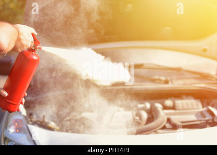 Ein Mann zeigt, wie ein Feuerlöscher über ein Auto Motor zu verwenden Stockfoto