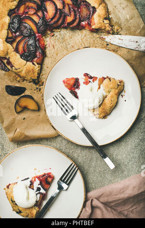 Flachbild-lay von Pflaume galetta süße Kuchen in weißen Platten mit Eis über grauer Beton Hintergrund diente, Ansicht von oben. Saisonale Fallen oder im Herbst Dessert Stockfoto