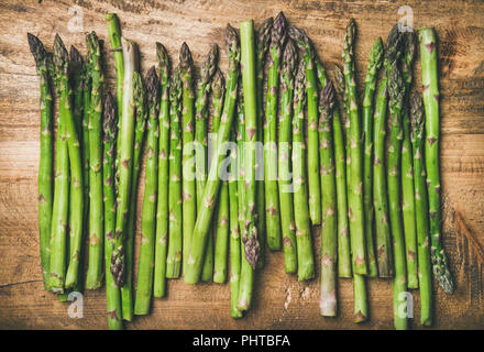 Saisonale Ernte produzieren. Flachbild-lay von Roh ungekocht grüner Spargel in der Zeile über rustikal Hintergrund, Ansicht von oben. Lokaler Markt essen Konzept Stockfoto