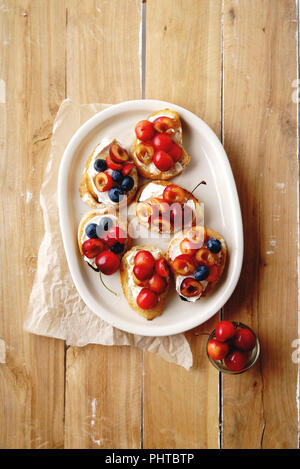 Bruschetta mit Kirsche, Heidelbeere, Honig Sauce und Frischkäse Stockfoto