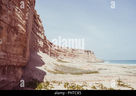 Hoch aufragenden roten Sandsteinfelsen Angolas Küste in der Namib Wüste. Stockfoto