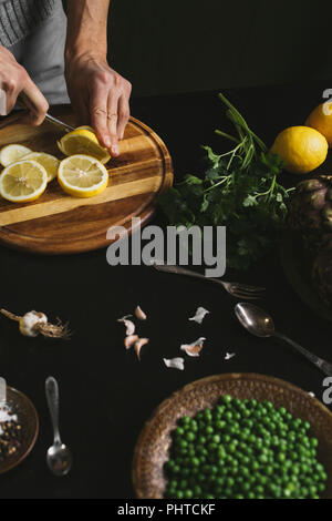 Ein Mann Schichten eine Zitrone und bereitet das Mittagessen Stockfoto