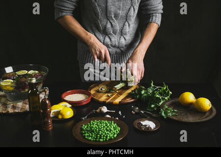 Ein Mann bereitet das Mittagessen mit Artischocken und Erbsen Stockfoto