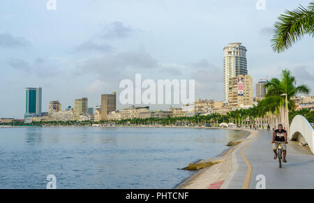 Luanda, Angola - 28. April 2014: Bucht von Luanda mit Strandpromenade und Mann auf dem Fahrrad auf bewölkten Tag. Stockfoto