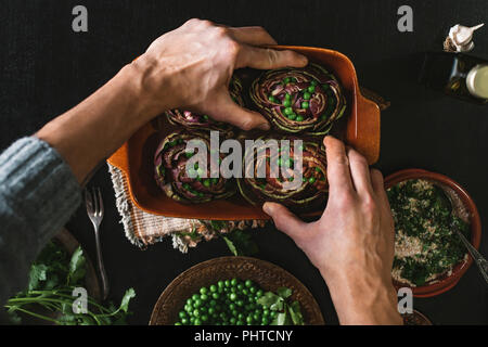 Ein Mann bereitet das Mittagessen mit Artischocken und Erbsen Stockfoto