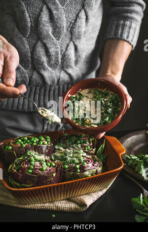 Ein Mann bereitet das Mittagessen mit Artischocken und Erbsen Stockfoto