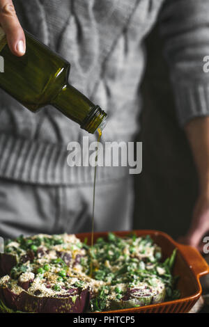 Ein Mann gießt hausgemachtes Olivenöl auf Artischocken Stockfoto