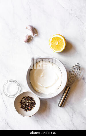 Zutaten für einen Salat Dressing, Joghurt, Zitronensaft, Pfeffer, Knoblauch. Stockfoto