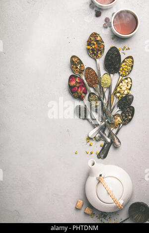 Sortiment von trockenen Tee in vintage Löffel, Teekanne und Tassen Tee. Kaffee Arten Hintergrund, Flach, Platz für Ihren Text oder Logo Stockfoto