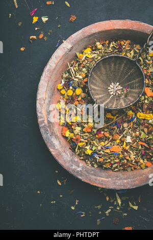 Kräuter und Blüten Tee mit alten Teesieb auf dunklem Hintergrund Stockfoto