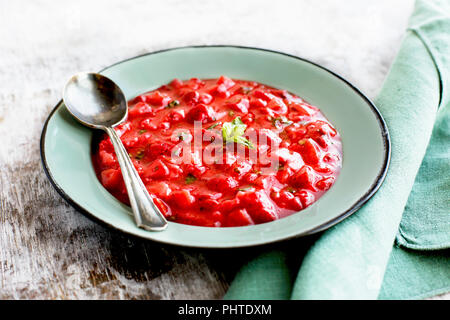 Erdbeere Basilikum Marmelade in einem Emaille Schüssel. Auf einem urigen weißem Hintergrund fotografiert. Stockfoto