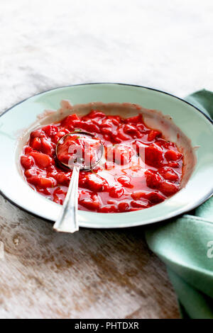 Erdbeere Basilikum Marmelade in einem Emaille Schüssel. Auf einem urigen weißem Hintergrund fotografiert. Stockfoto